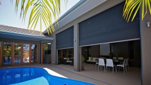 View of outdoor living area with pool, hinged patio doors, and large zip screens.